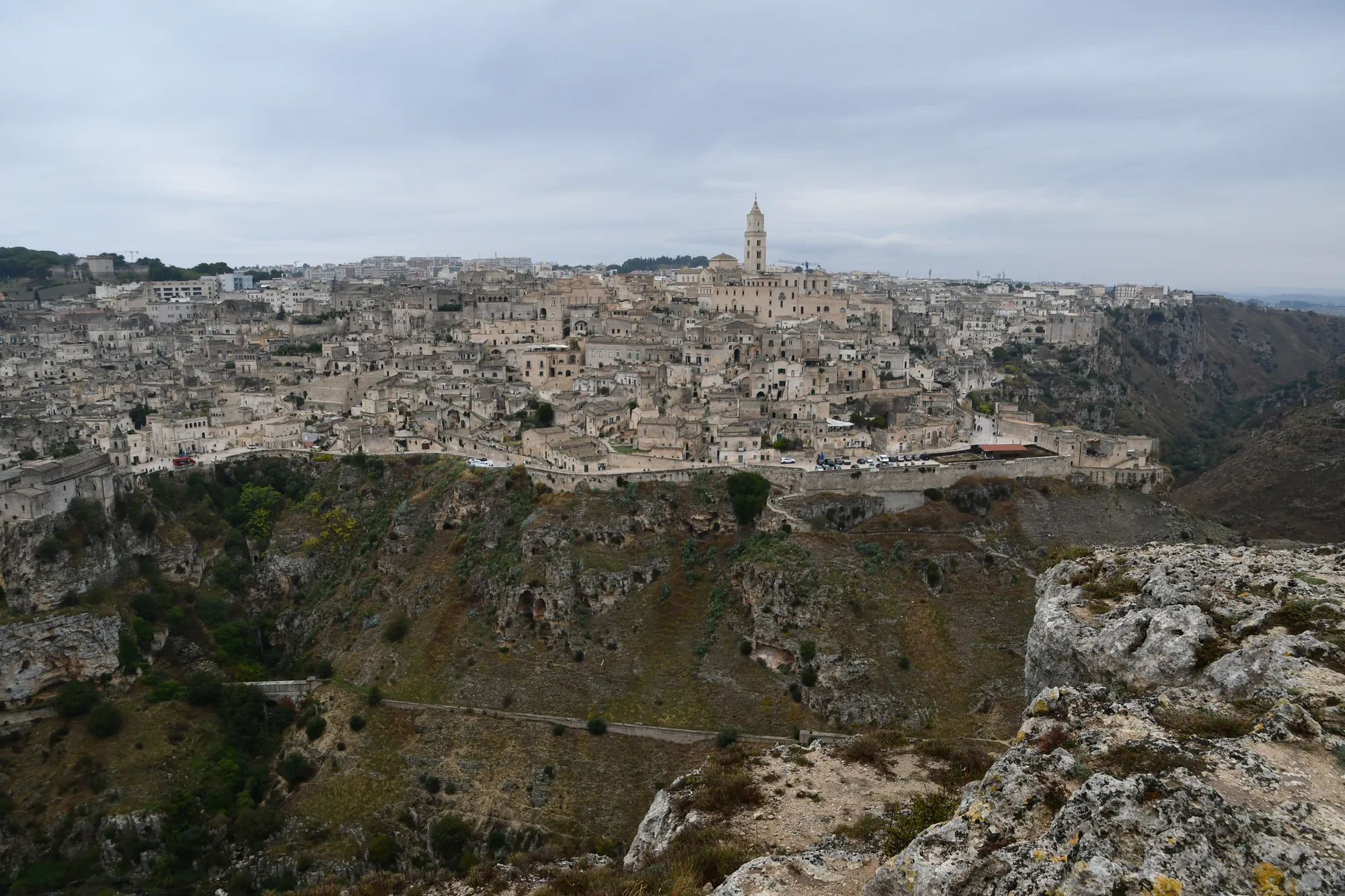 Uitzicht over het ravijn van de Gravina naar Matera onder een bewolkte lucht