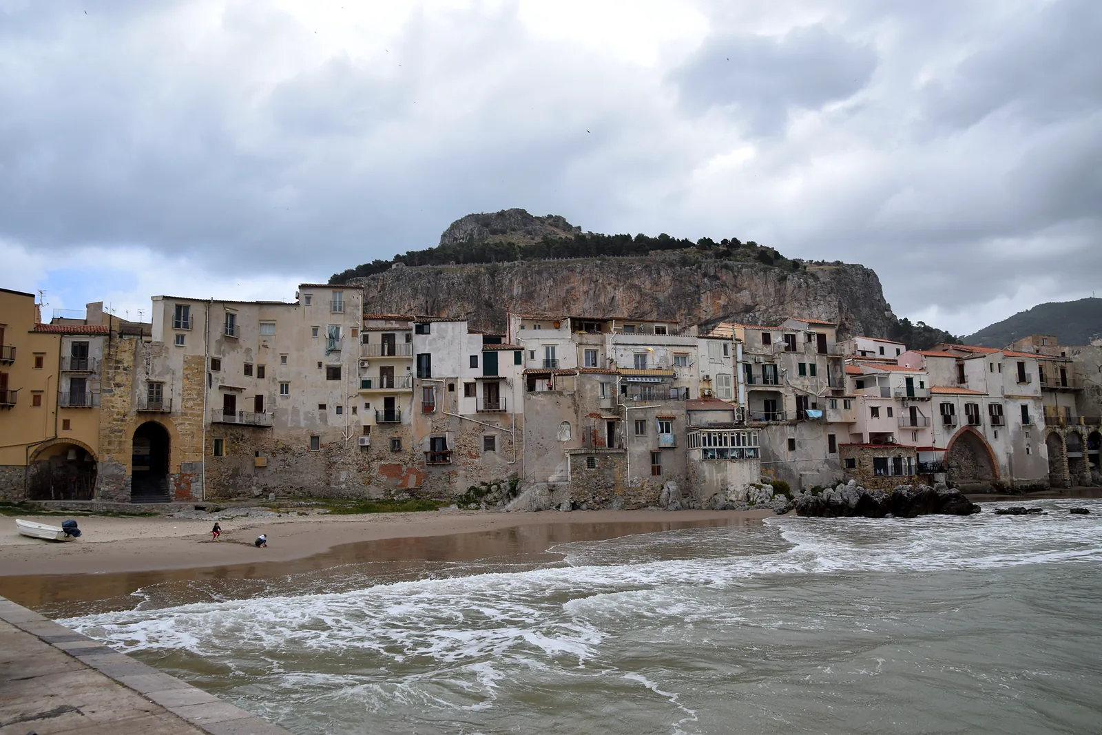 Oude huizen van Cefalù aan het strand met de rots La Rocca erachter
